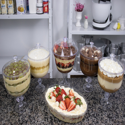 Uma mesa cheia de sobremesas na taça com uma bandeja de sobremesa no meio das taças